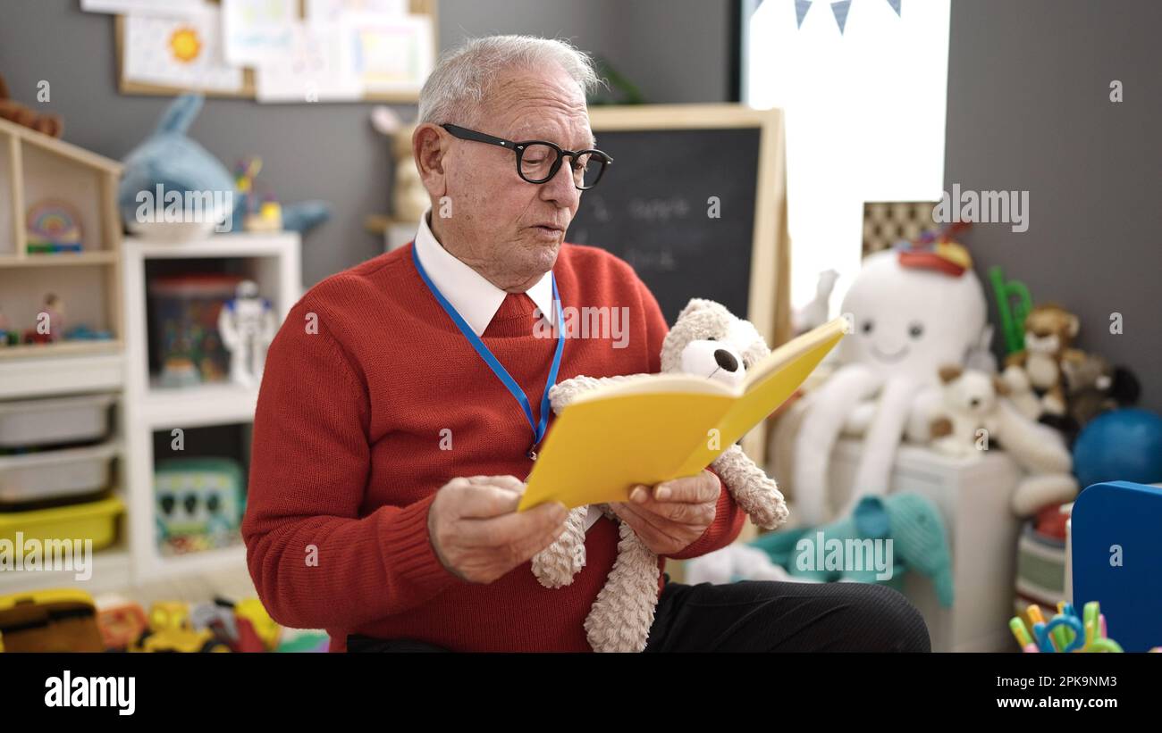 senior preschool teacher reading book at kindergarten Stock Photo