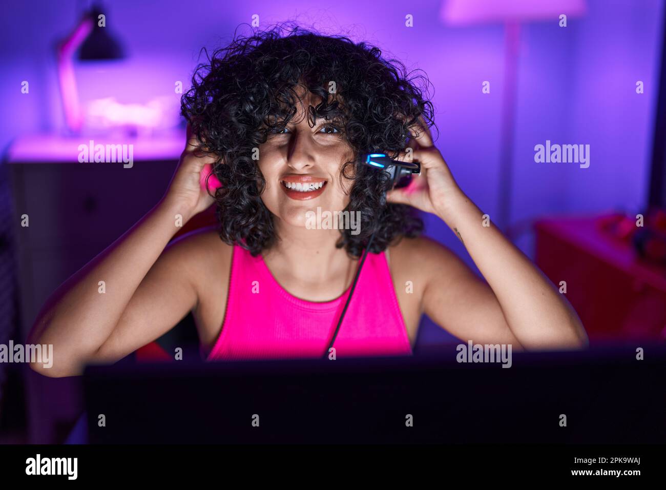 Young middle eastern woman streamer smiling confident sitting on table