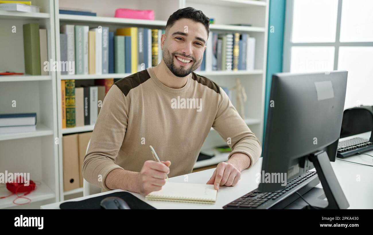 Young arab man student using computer writing on notebook at university ...