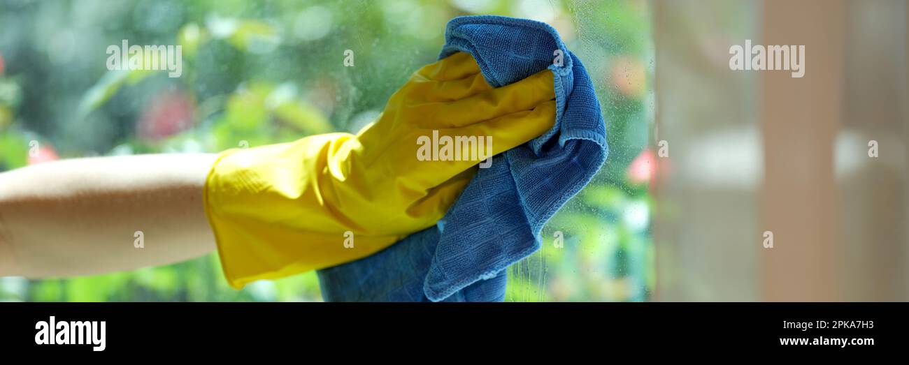 Woman cleaning window using detergent and rags Stock Photo