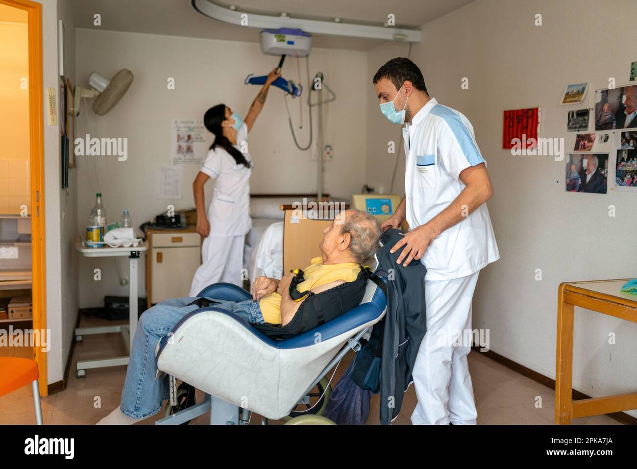 Two nursing assistants put a disabled patient to bed in her room at the ...