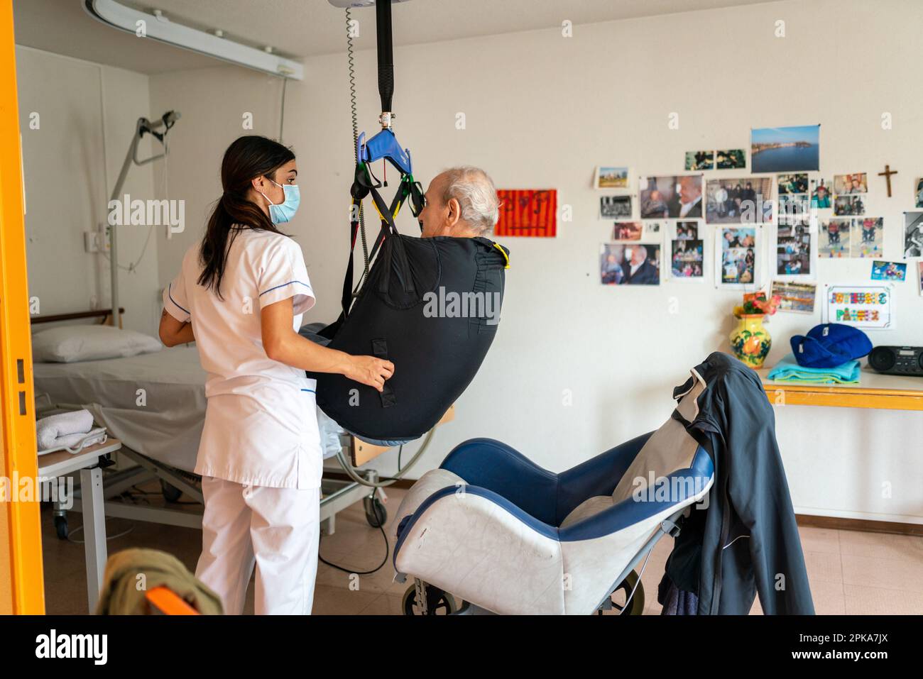 Caregiver preparing the bedtime of a disabled patient in his room at the retirement home. Stock Photo