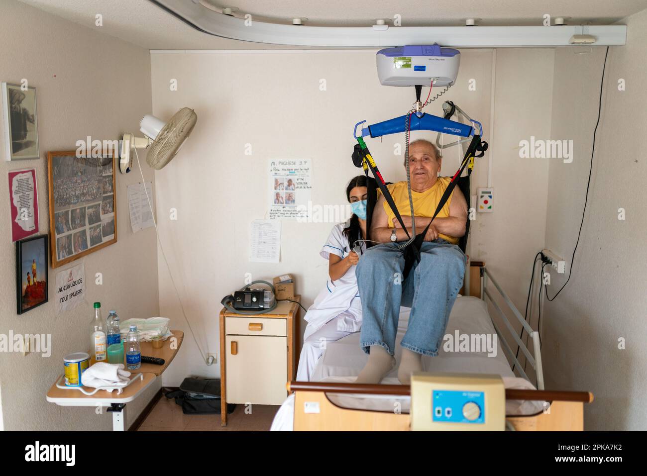 Caregiver preparing the bedtime of a disabled patient in his room at the retirement home. Stock Photo