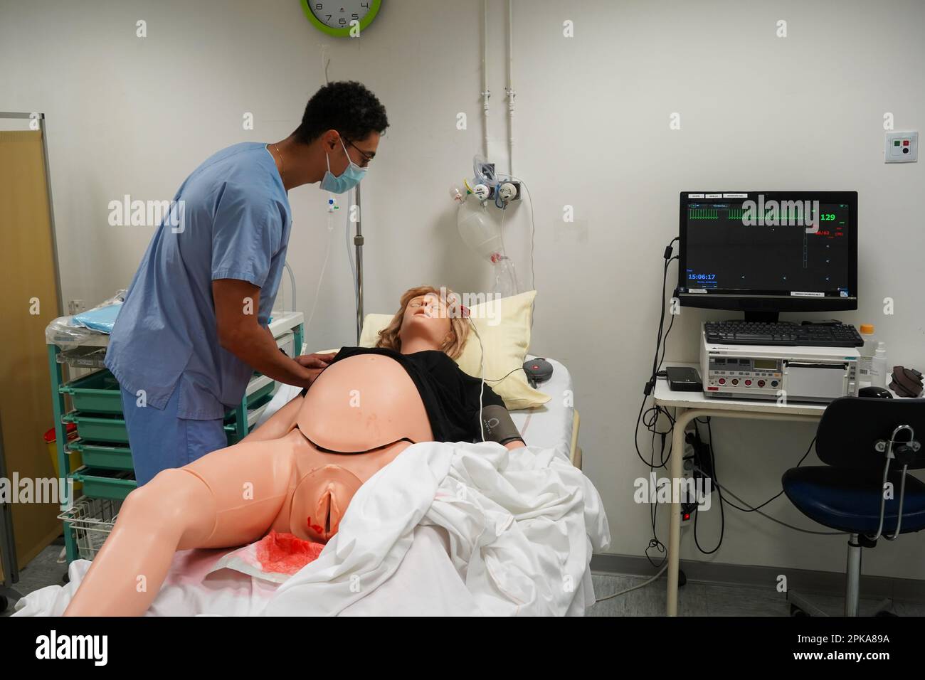 Students facing a post natal emergency follow procedures on a mannequin. This dummy is controlled by operators in an adjoining room. Stock Photo