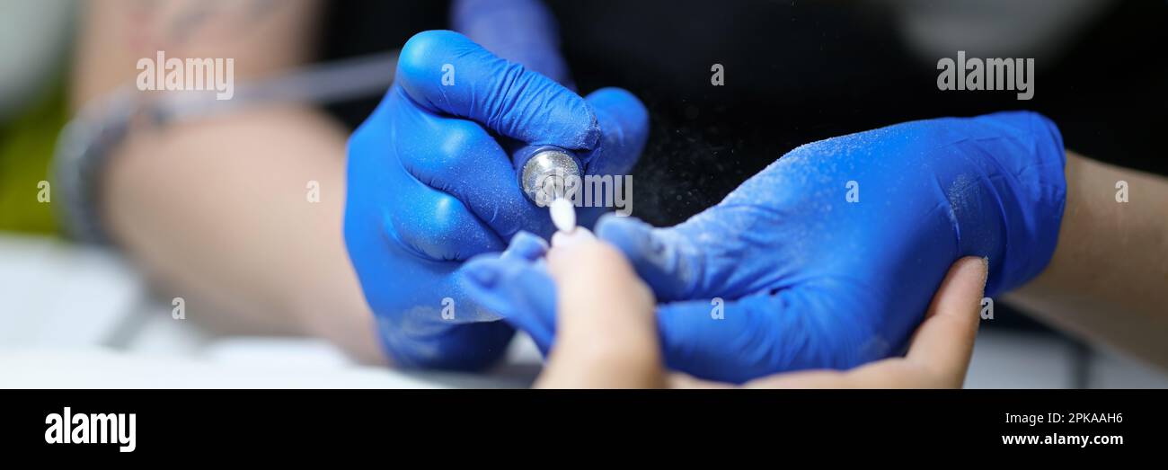 Nail specialist doing manicure to client using special apparatus