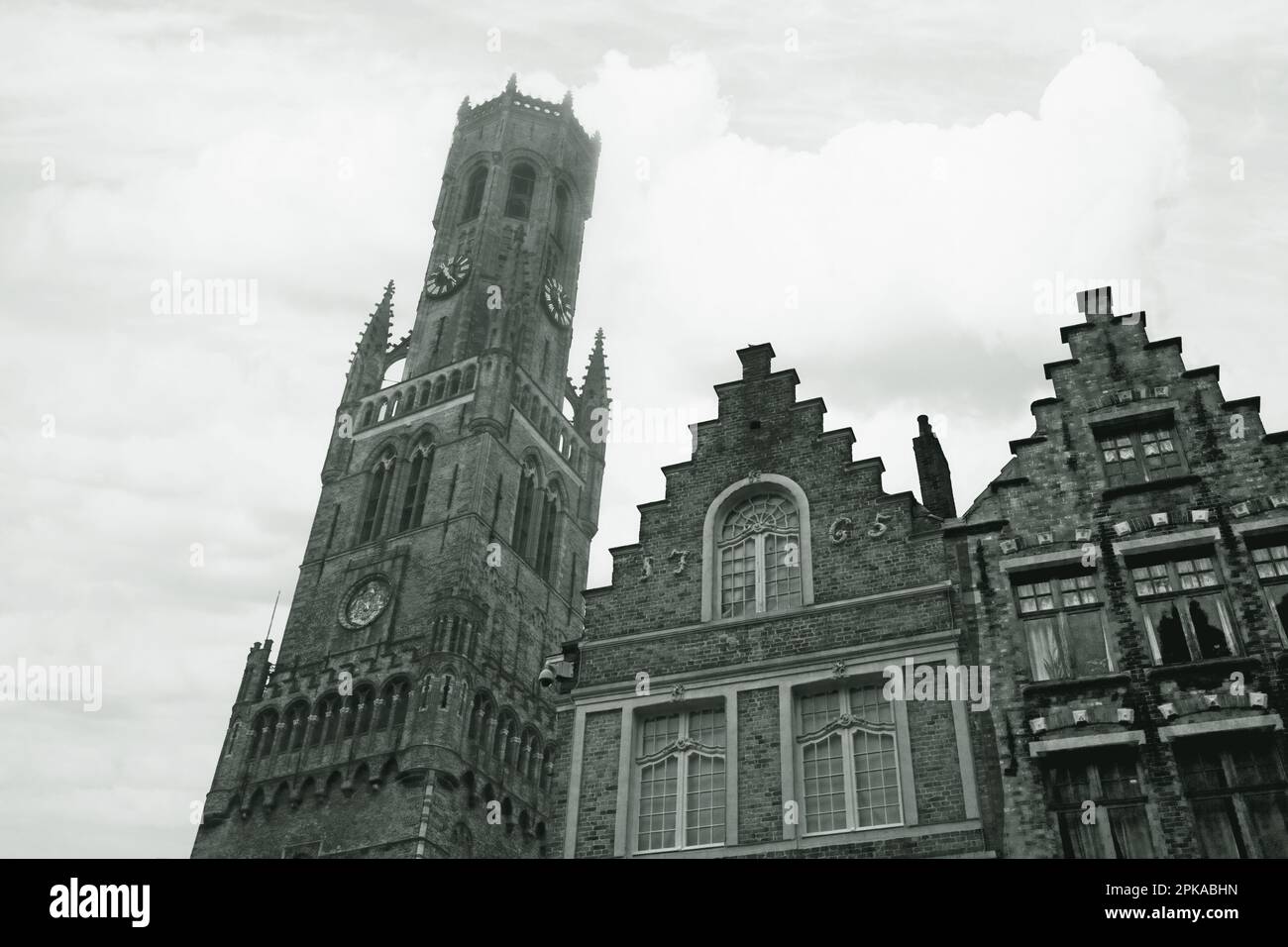 The Belfort, or Belfry Tower ascends into February mist, flanked by venerable medieval buildings in the Grote Markt, Brugge, Belgium Stock Photo