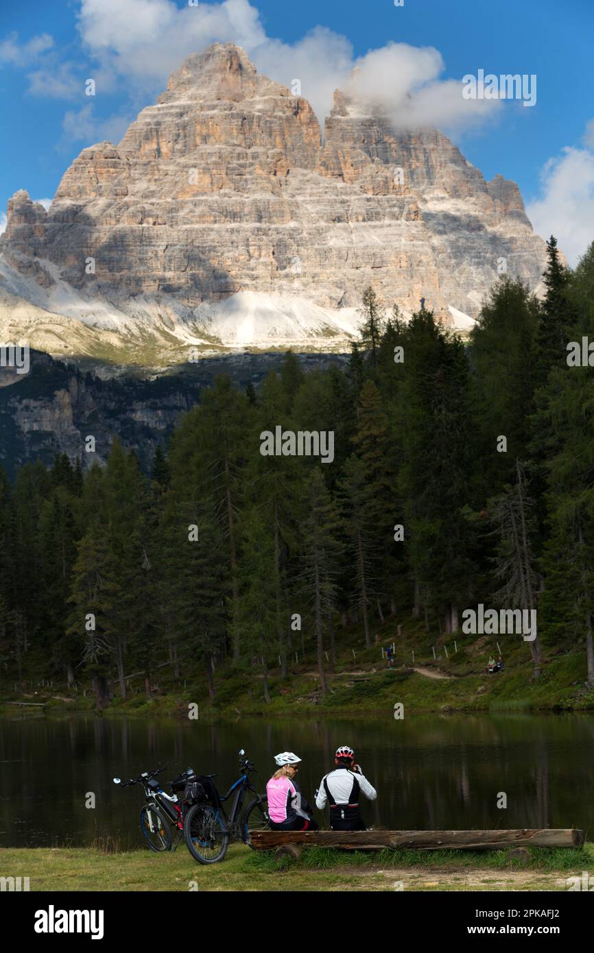 08.09.2021, Italy, Veneto, Belluno - Cyclists resting at Lago di Antorno. In the background the Three Peaks, Tre Cime di Lavaredo. 00U210908D002CAROEX Stock Photo