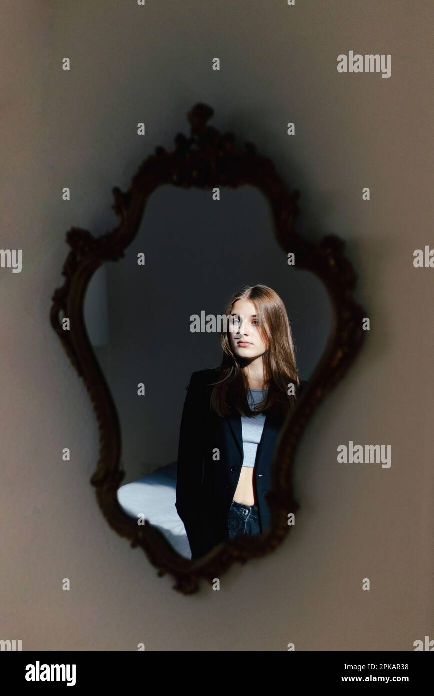 Girl looks at her reflection in wall mirror Stock Photo - Alamy