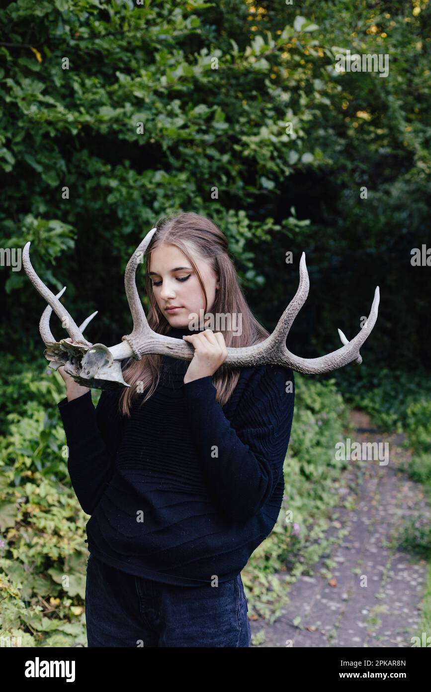 Girl with closed eyes holding big antlers Stock Photo