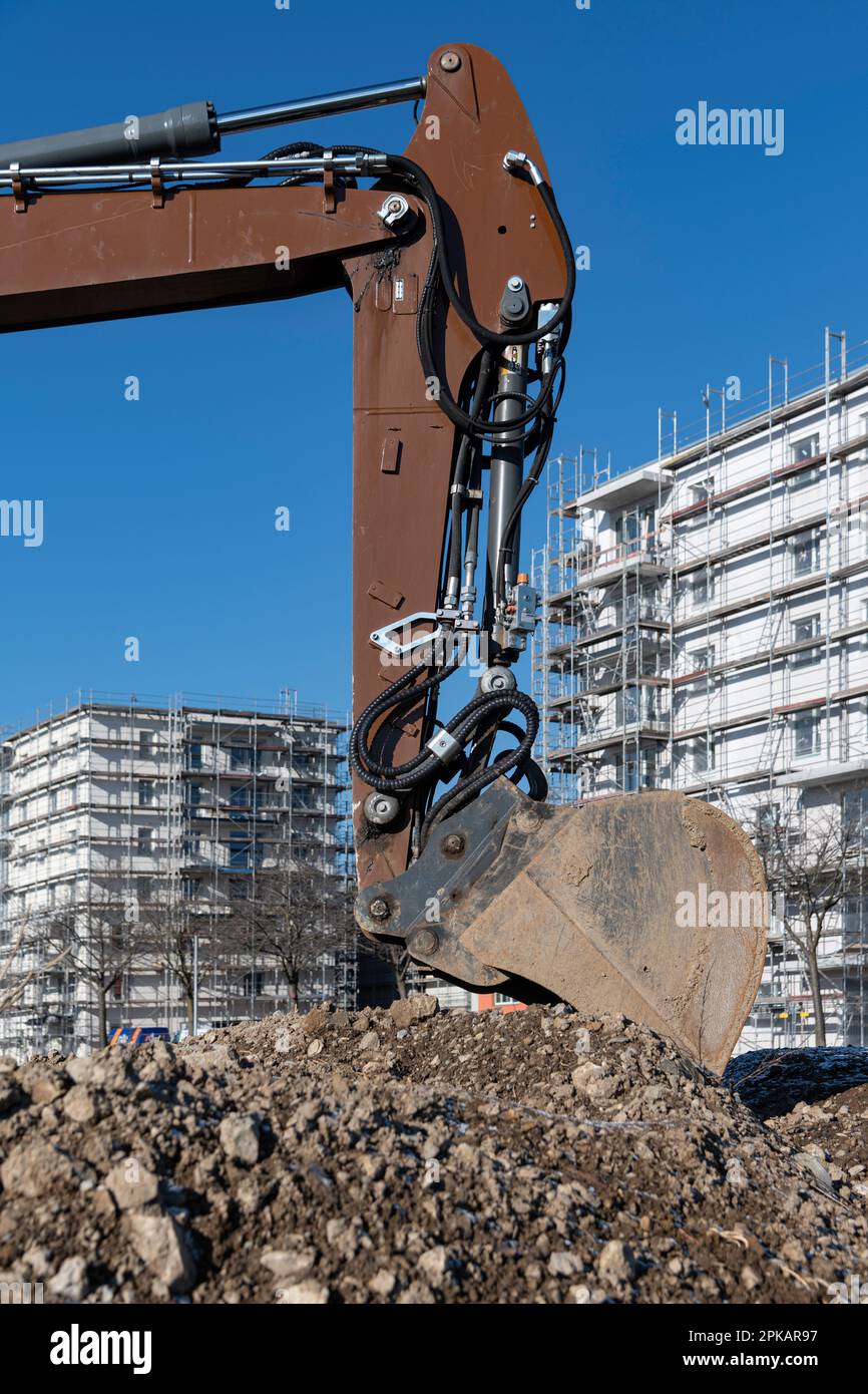 Shovel of brown excavator stands on large construction site with multistorey shell buildings in