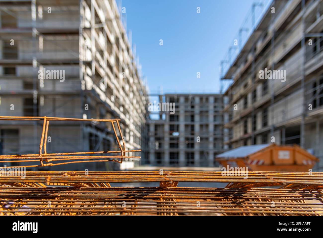 Rusty steel probation lies stacked on the ground at a large construction site with multi-story buildings in the shell in the background Stock Photo