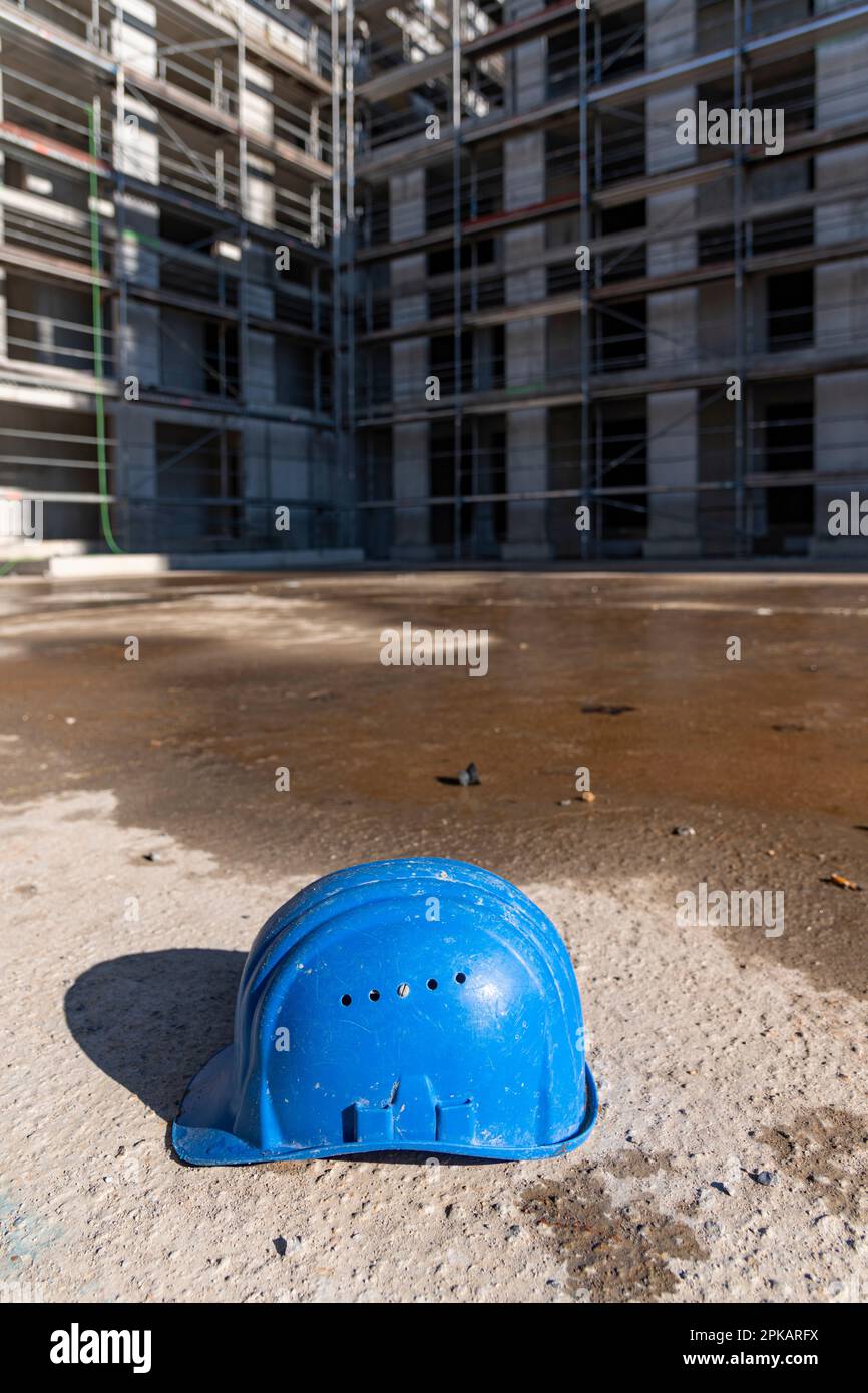 Blue construction worker helmet lies on the ground of abandoned construction site Stock Photo