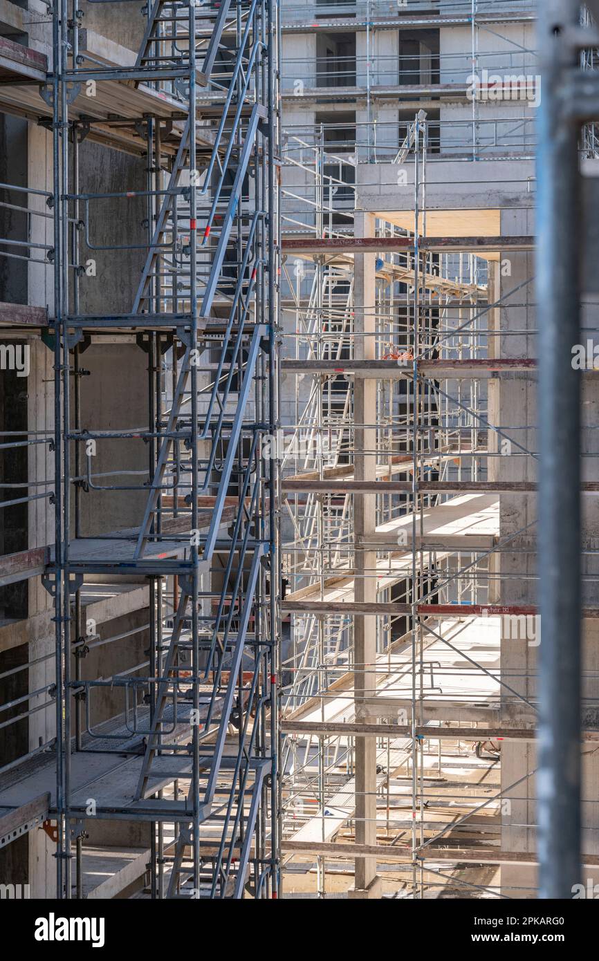 Detail of facade of scaffolded multi-storey building in shell with exciting back light Stock Photo