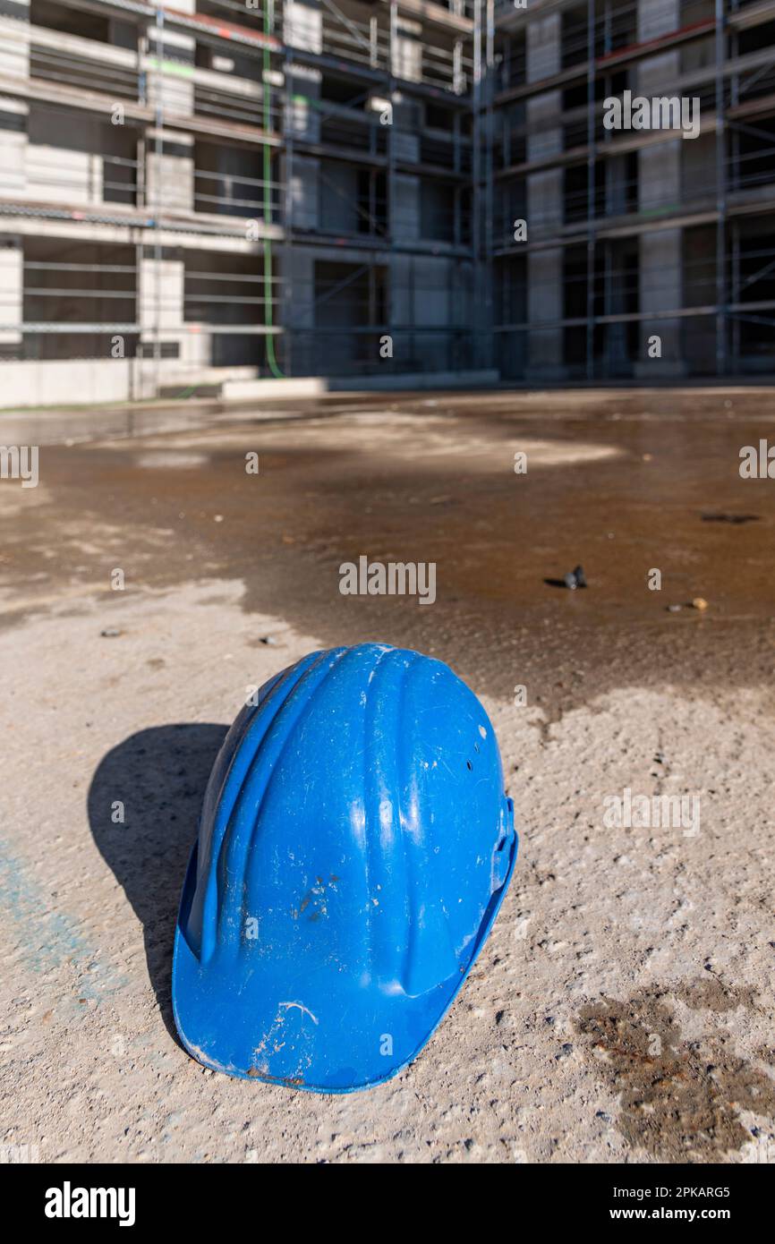 Blue construction worker helmet lies on the ground of abandoned construction site Stock Photo