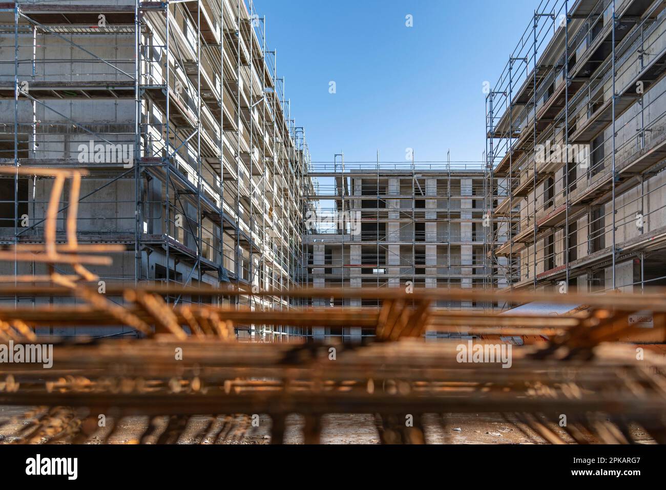 Rusty steel probation lies stacked on the ground at a large construction site with multi-story buildings in the shell in the background Stock Photo