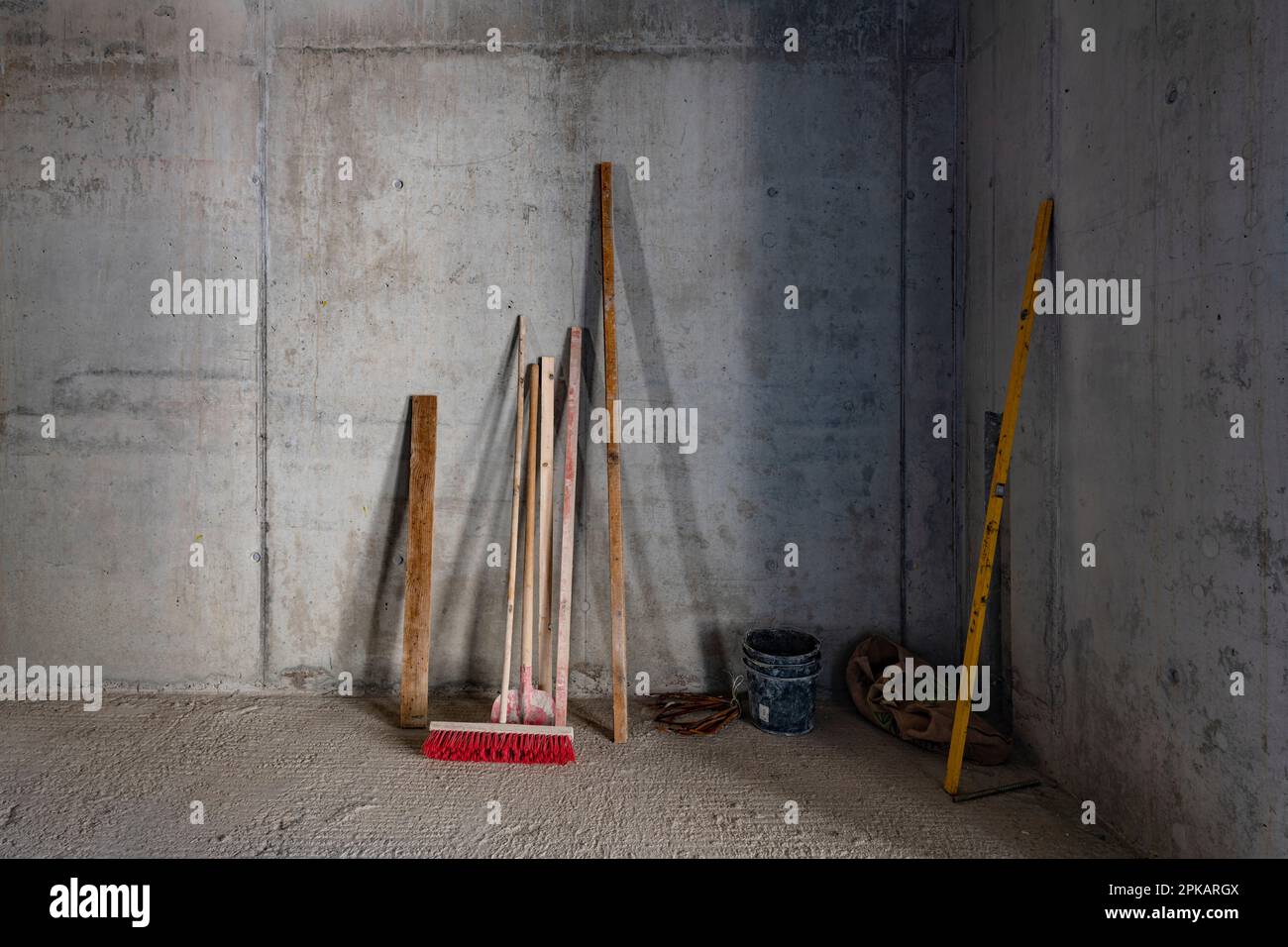 Shovel broom and wooden beam leaning against concrete wall on construction site Stock Photo