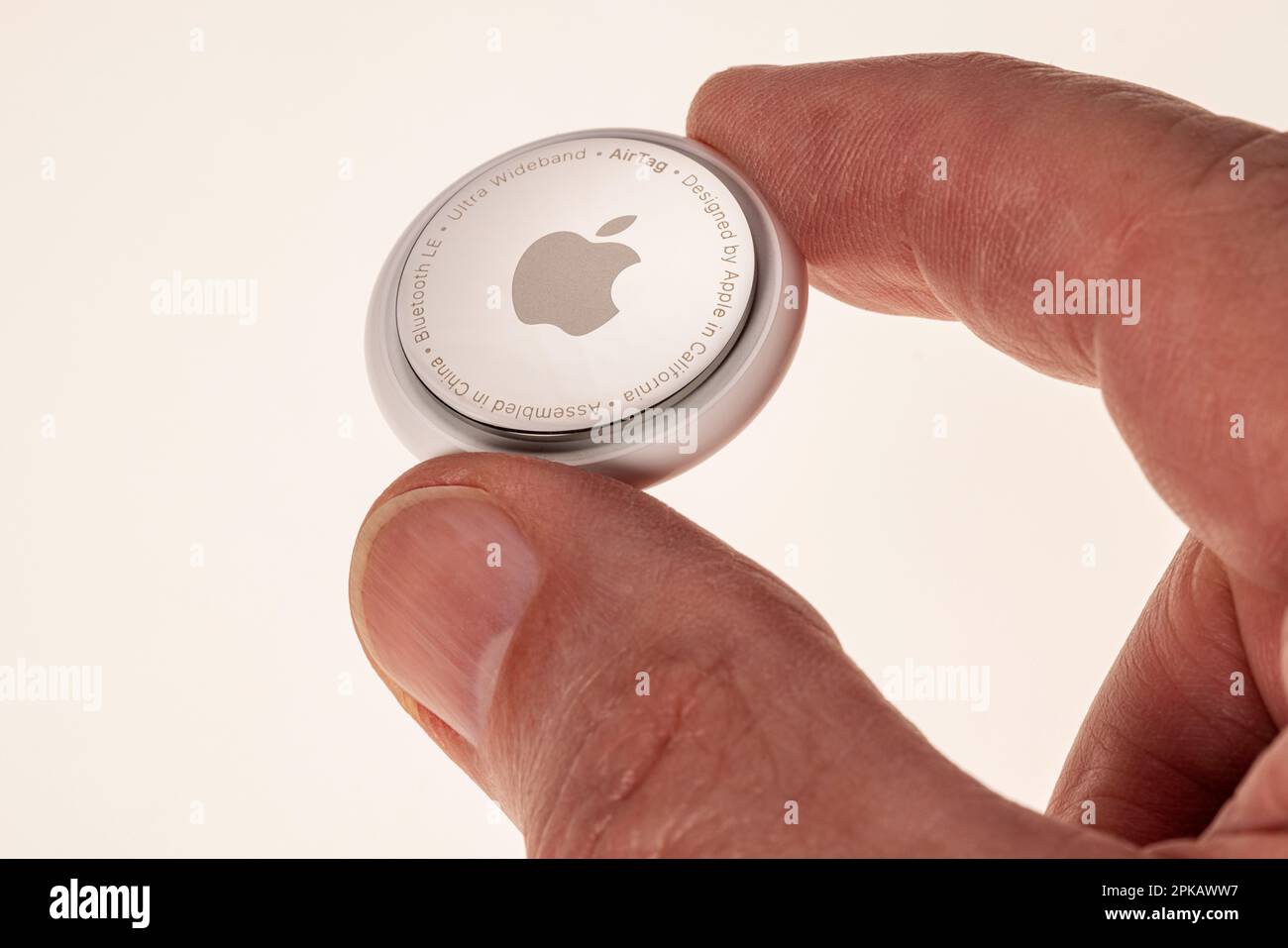 Man hand holding Apple AirTag, icon image, tracking tag, key finder, white background, Stock Photo