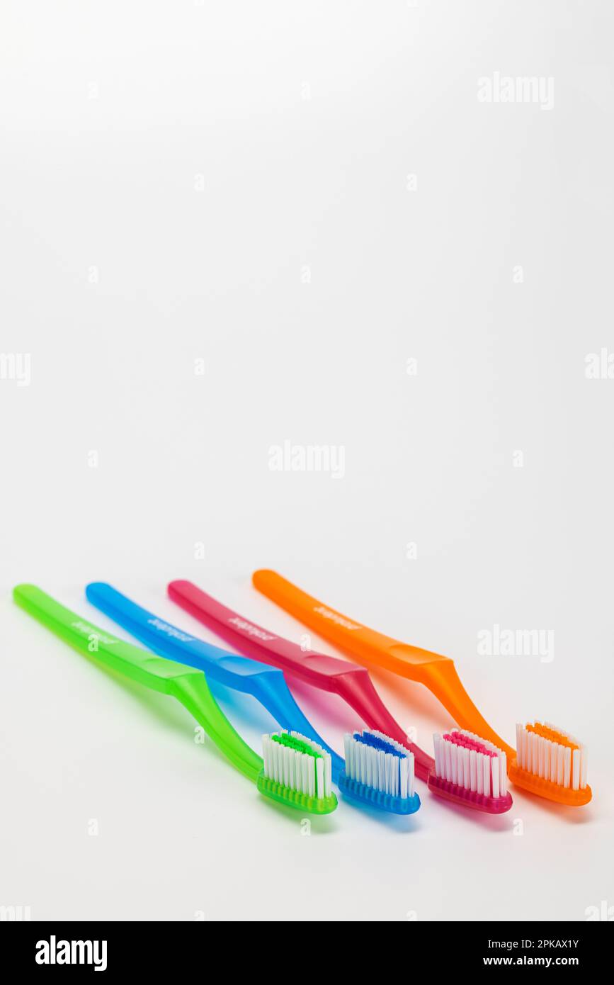 Four different colored manual toothbrushes, white background, symbol