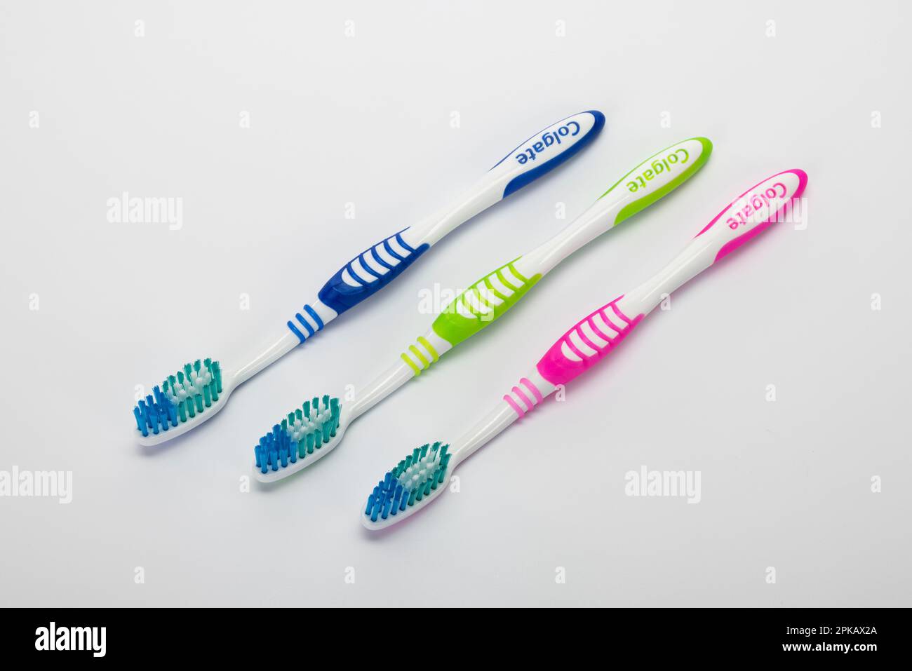 Three different colored manual toothbrushes, white background, symbol