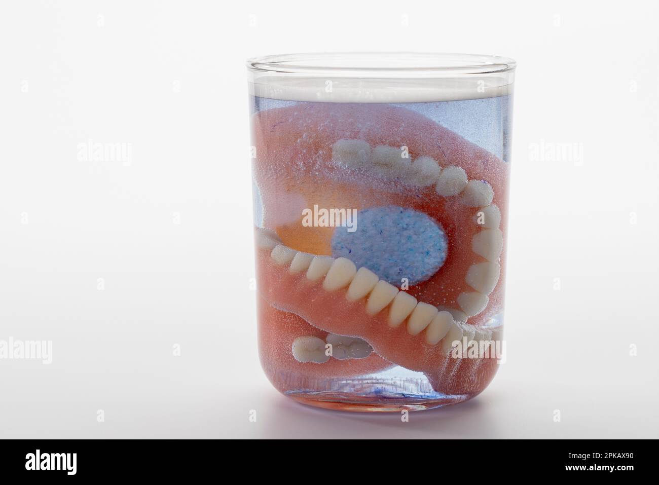 Denture with cleaning tablet in water glass, symbol image, clean