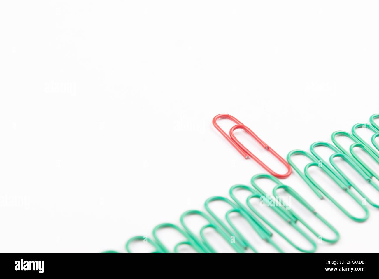 Single red paperclip between green paperclip, leader and unique concept