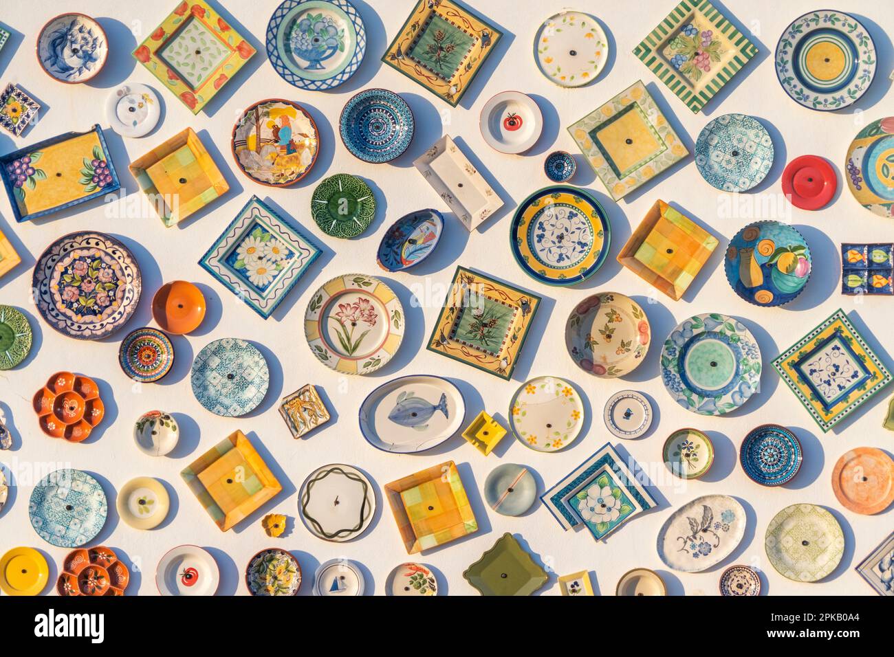 Traditional portuguese pottery, local handcrafted products from Portugal. Wall of ceramic plates in Portugal. Colorful vintage ceramic plates in Sagre Stock Photo