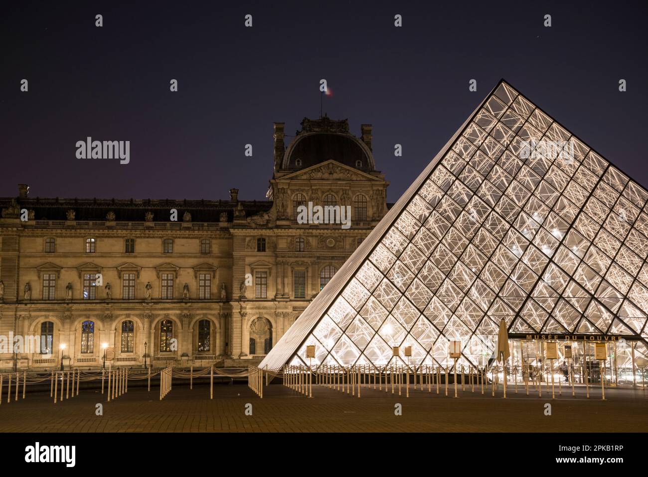 The famous Louvre Palace and its iconic glass pyramide at night, Paris