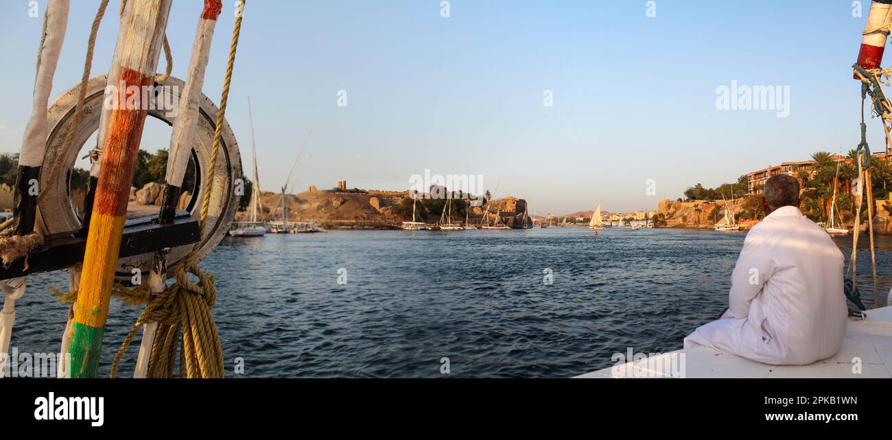 Captain of an Egyptian sailboat enjoying his return journey in the evening sun, Aswan, Egypt Stock Photo