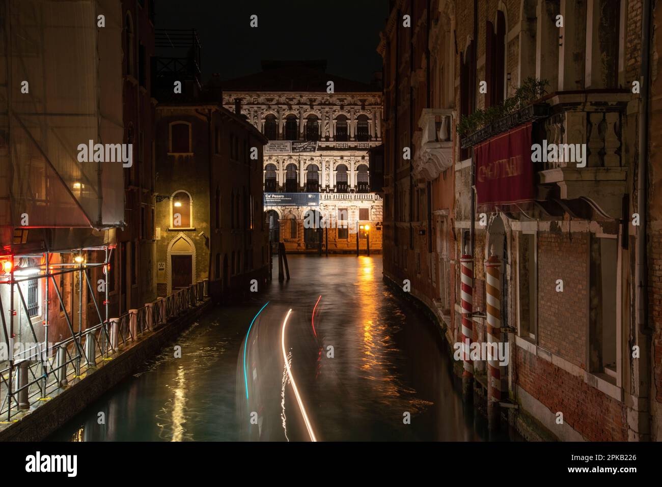 View to the Ca Pesaro International Museum of Modern Art at Night, a Boat driving on the rio di San Falice, Venice, Italy Stock Photo