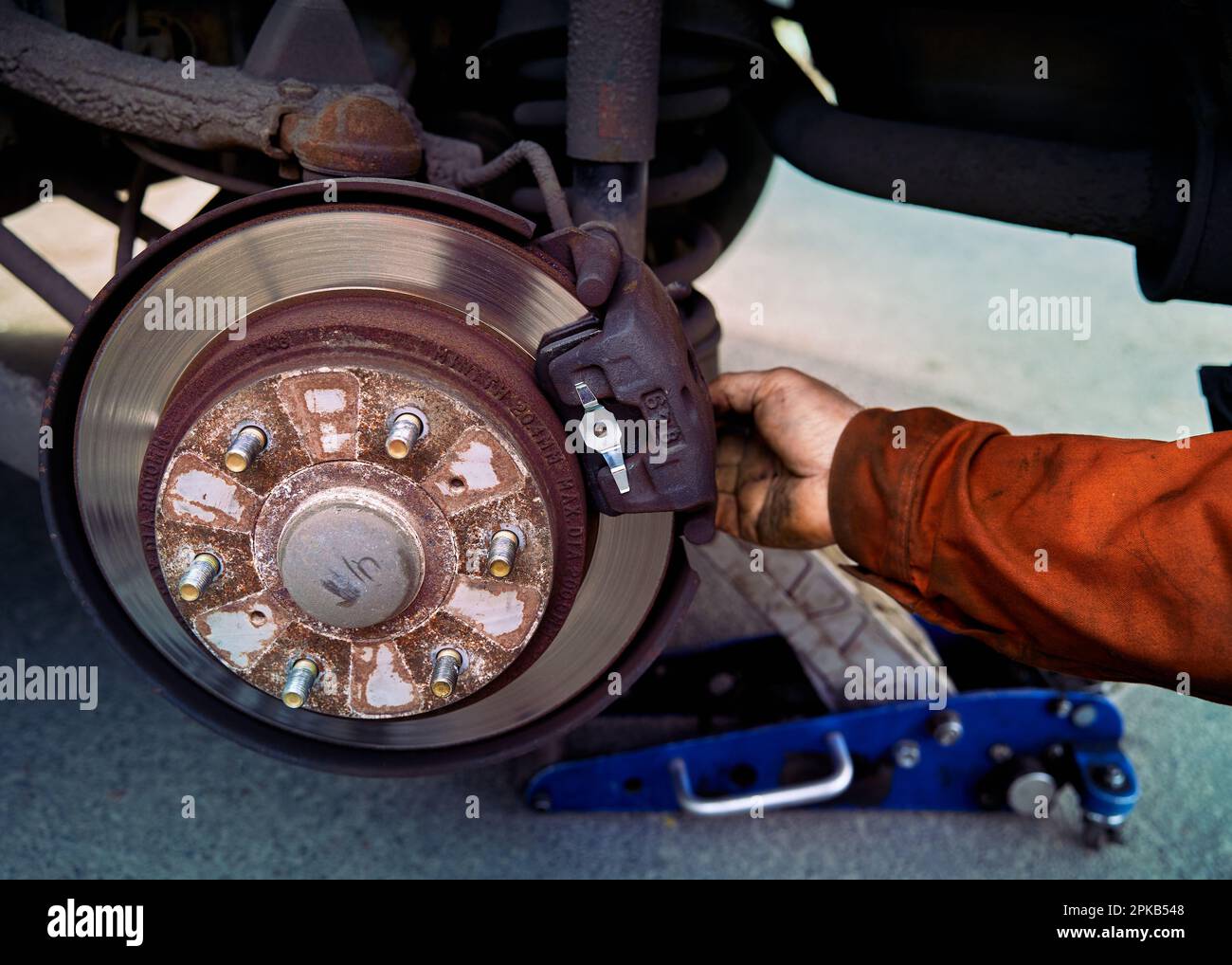 Car rusty brake rotor in automobile front photo with jack and