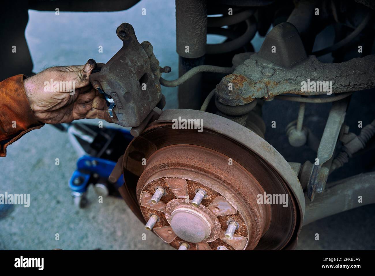 Car rusty brake rotor in automobile workshop photo with mechanic hand Stock Photo