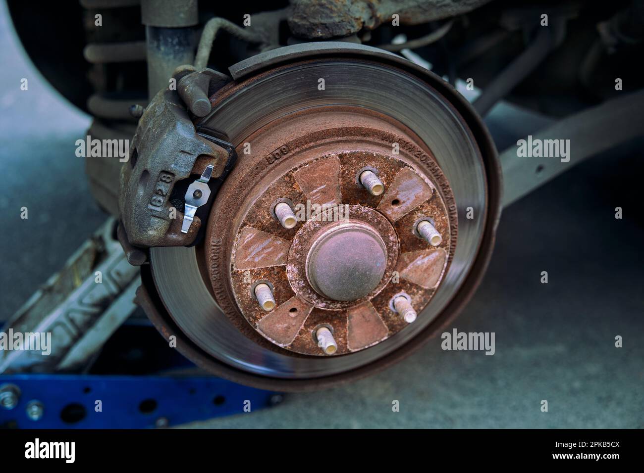 Car rusty brake rotor in automobile workshop photo with jack Stock Photo