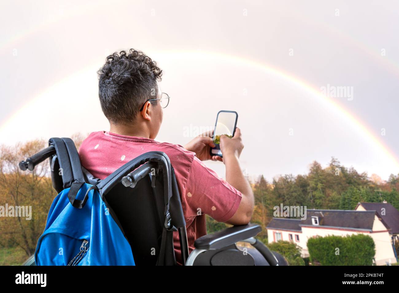 Teenager in a wheelchair facing a rainbow Stock Photo - Alamy