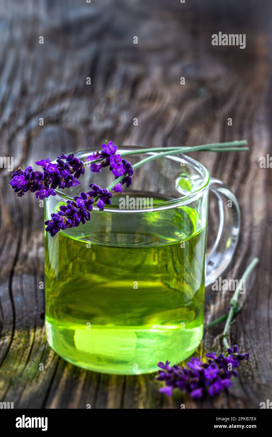 Sprigs of lavender (lavandala angustifolia) lying on glass cup. Stock Photo