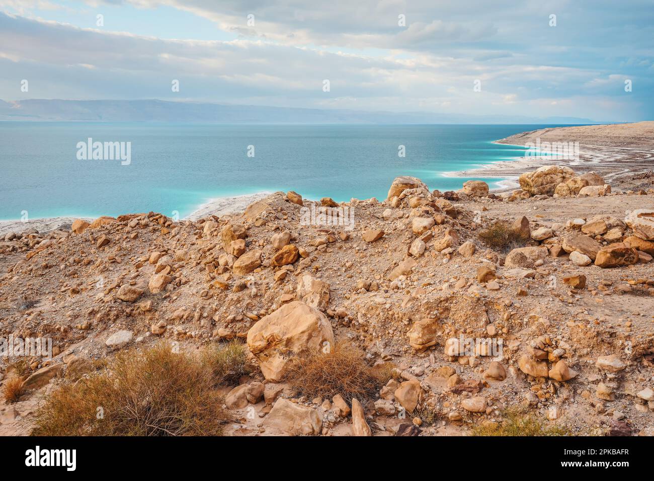 Dead sea shore at Jordan side, dry sand and rocks beach, sun shines on ...