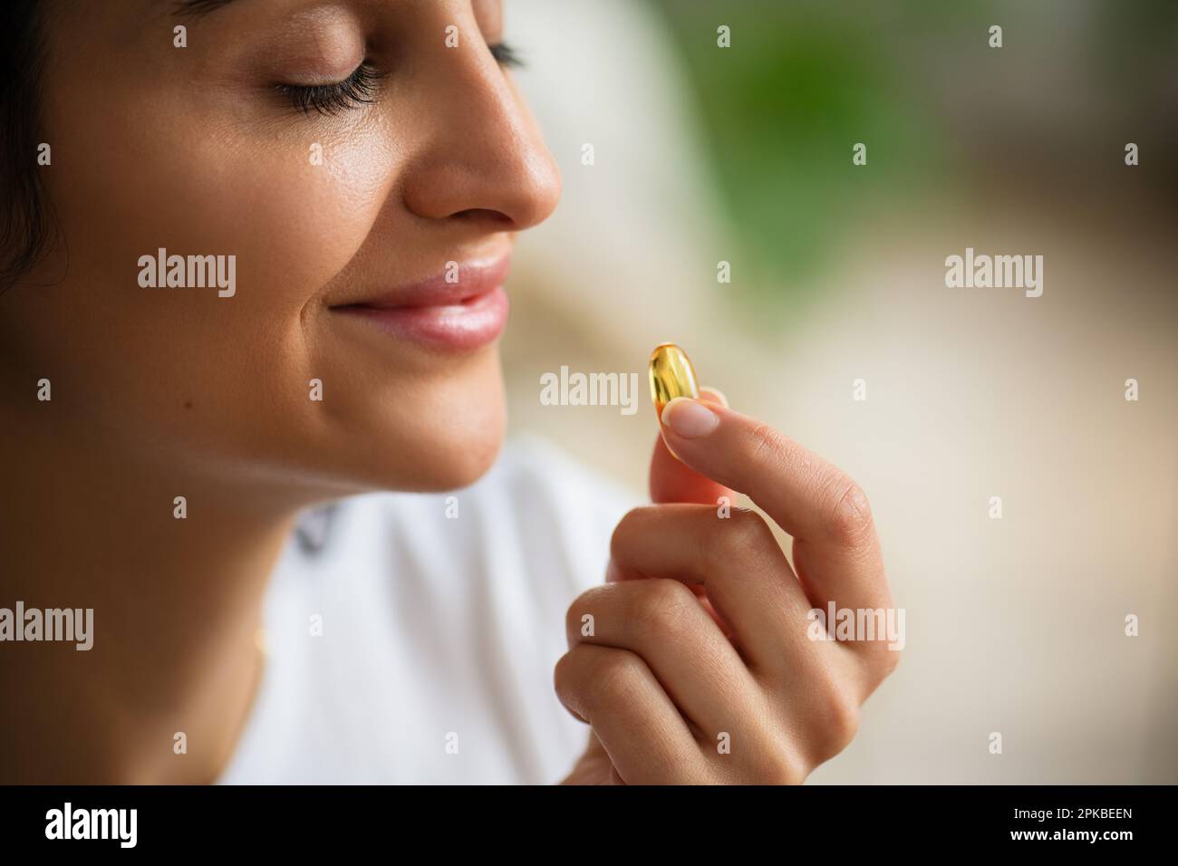 Multiracial smiling young woman taking a Fish Oil Omega3 capsule at