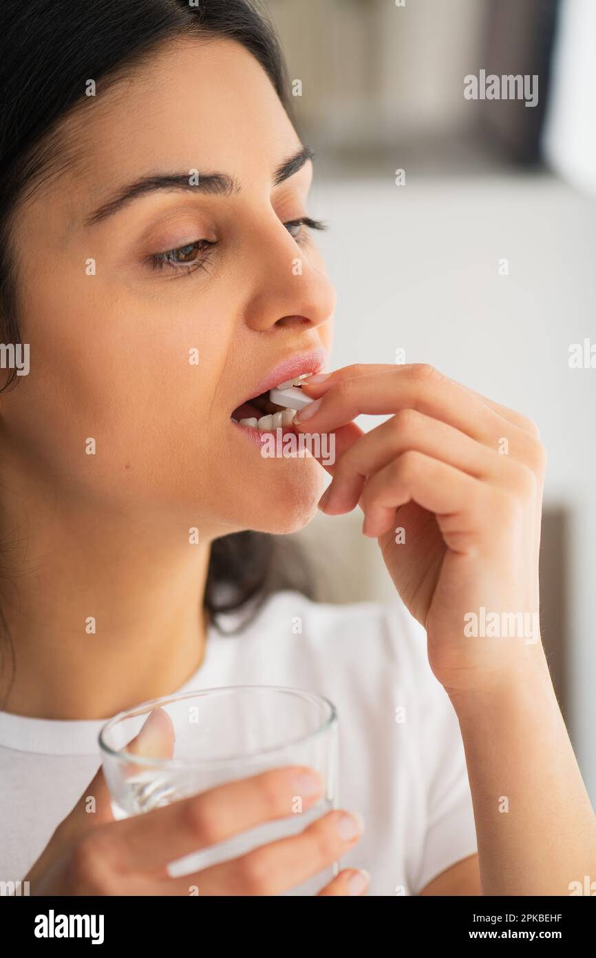 Multiracial young woman ready white pill of calcium with a glass of water in hand, Healthy lifestyle in prevention and treatment of diseases Stock Photo