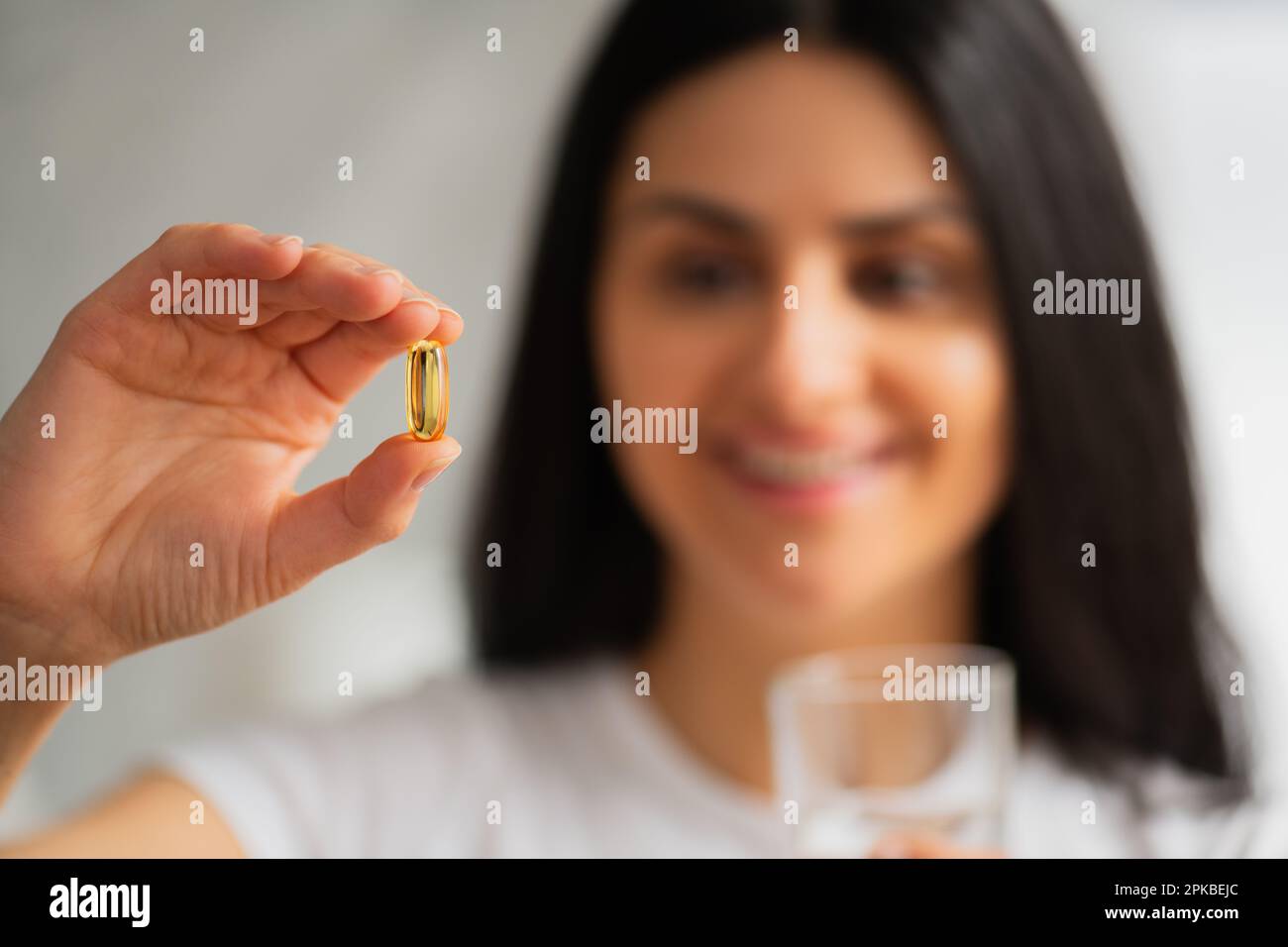 Multiracial Asian smiling young woman taking a Fish Oil Omega3 capsule