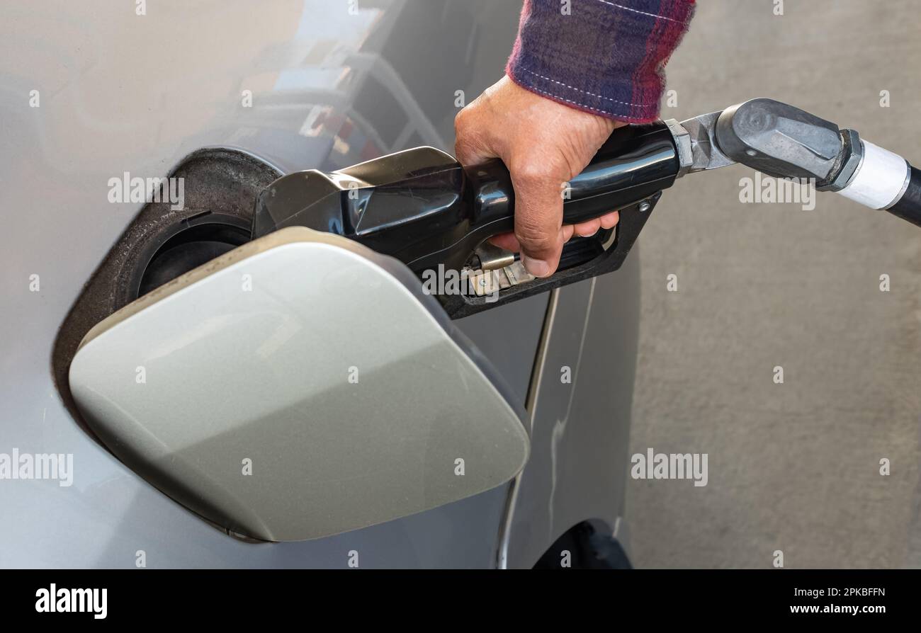 Refueling the car at a gas station fuel pump. Man driver hand refilling and pumping gasoline oil the car with fuel at refuel station. Car refueling on Stock Photo