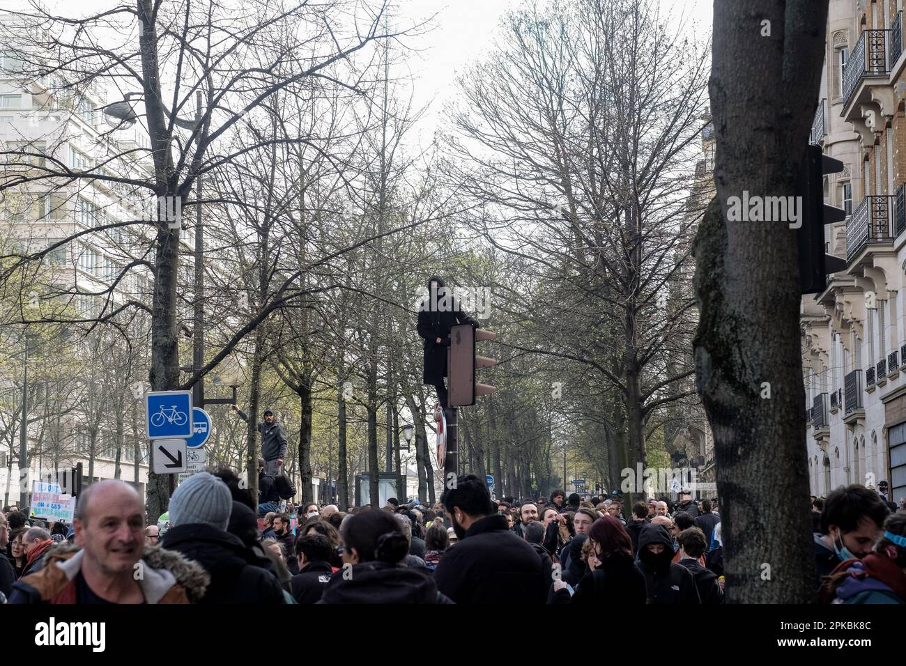 Paris, France. 6th Apr 2023. Michael Bunel / Le Pictorium -  Demonstration against pension reform in Paris  -  6/4/2023  -  France / Paris  -  A hooded protester watches the crowd from the traffic light he is standing on. Eleventh day of mobilisation against the pension reform, the use of 49.3 and the policies of Emmanuel Macron's government. 6 April 2023. Paris, France. Credit: LE PICTORIUM/Alamy Live News Stock Photo