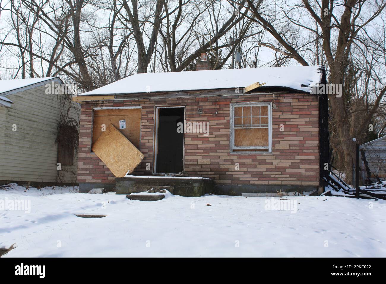 Boarded up abandoned stone-paneled home in Detroit's Brightmoor neighborhood in winter Stock Photo