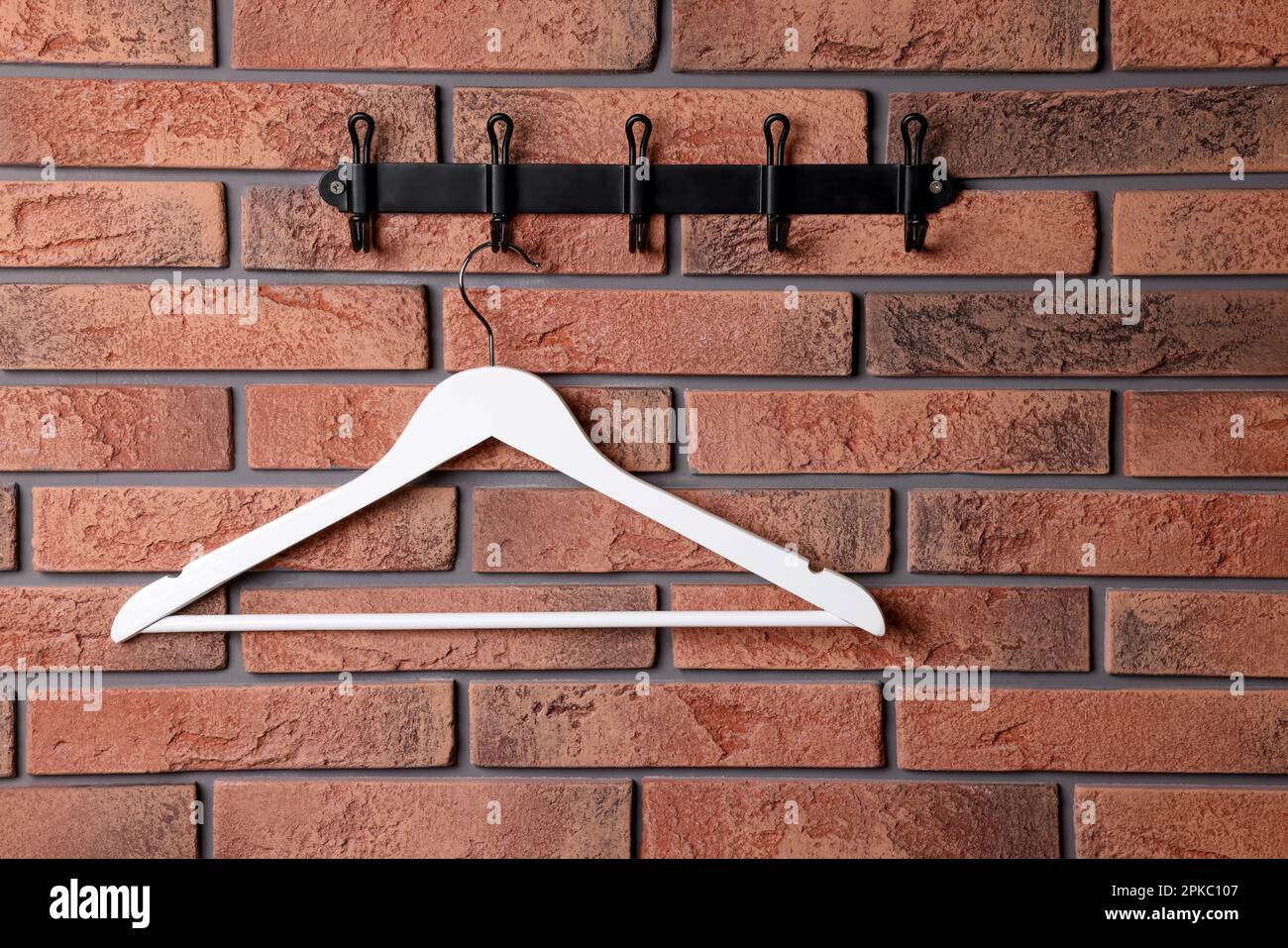 Hook rack with white clothes hanger on red brick wall Stock Photo