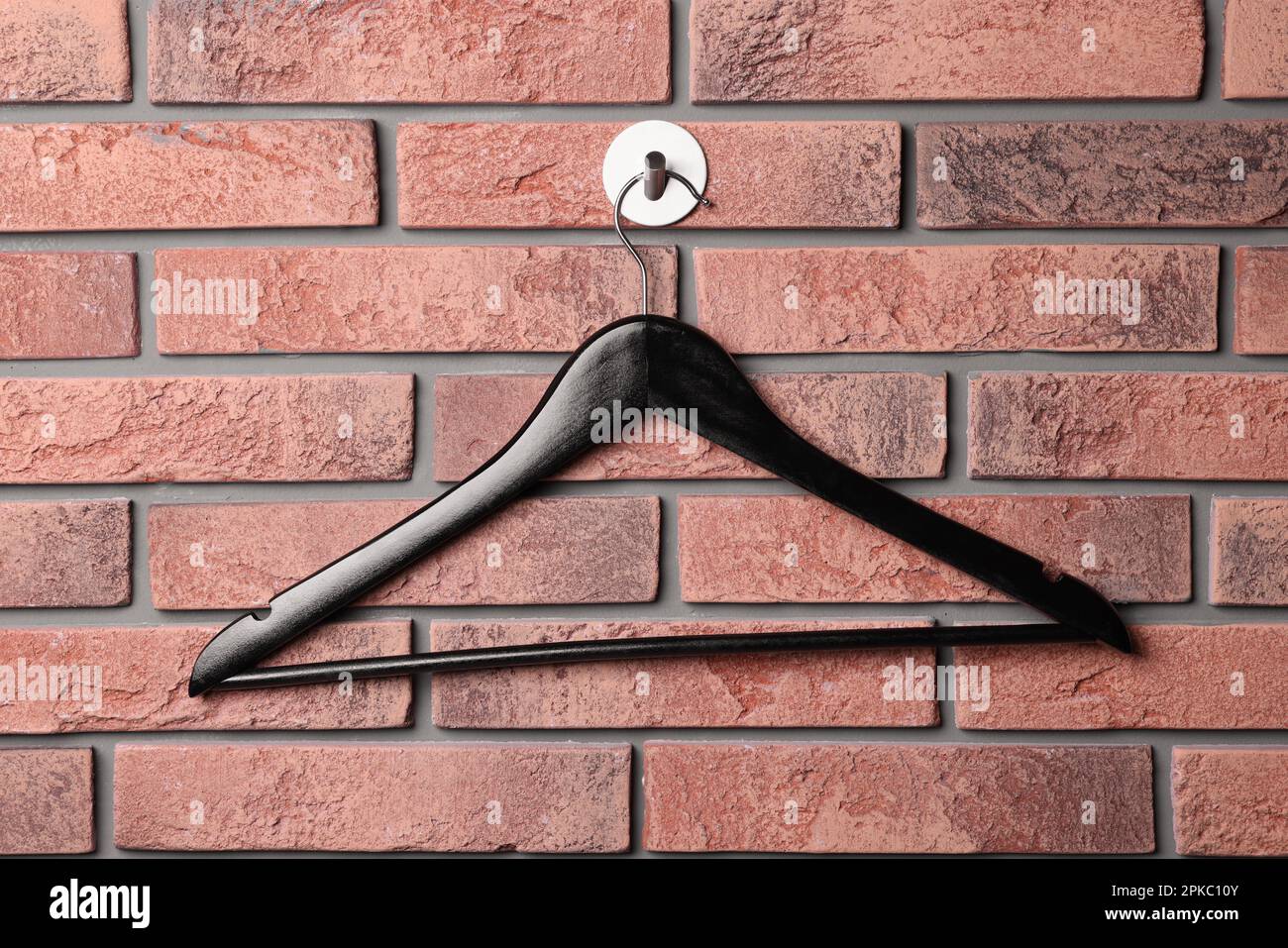 Black clothes hanger on red brick wall Stock Photo