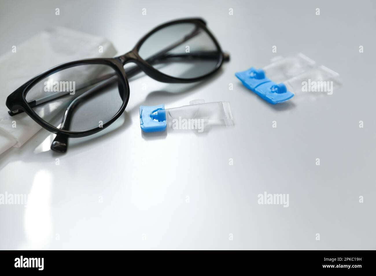 Single dose eye drops, glasses and fabric on white table. Space for