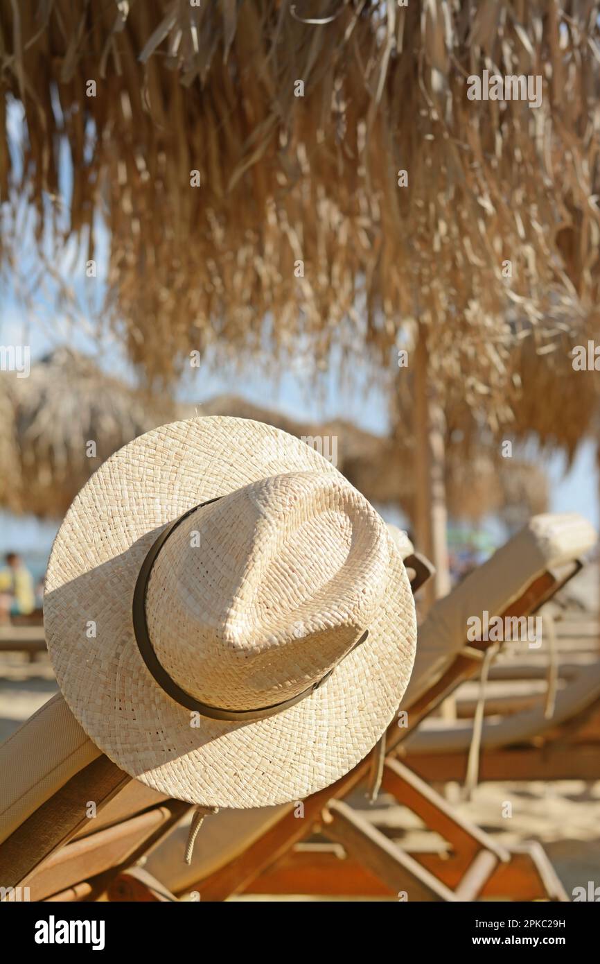 Stylish straw hat on wooden sunbed at beach Stock Photo - Alamy