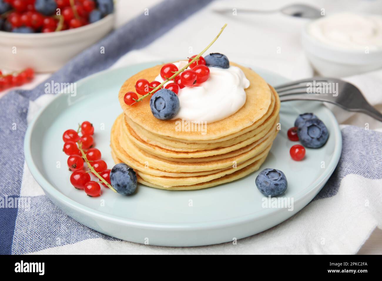 Tasty pancakes with natural yogurt, blueberries and red currants on table Stock Photo
