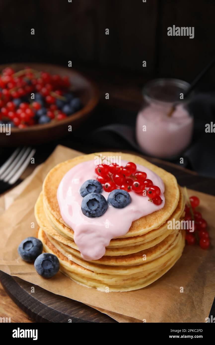 Tasty pancakes with natural yogurt, blueberries and red currants on table Stock Photo