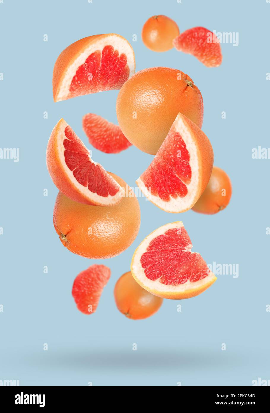 Tasty ripe grapefruits falling on light background Stock Photo