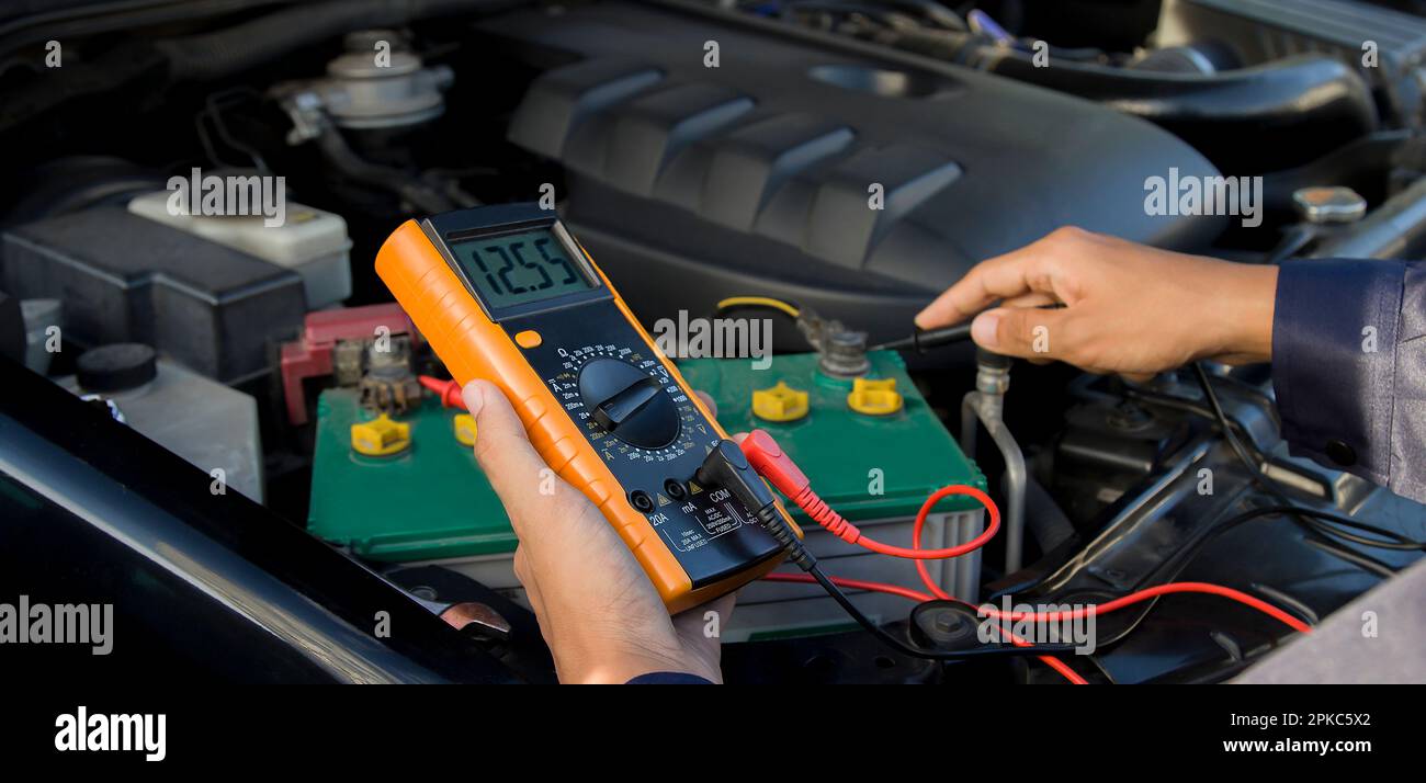 A technician is checking the car battery for availability Stock Photo
