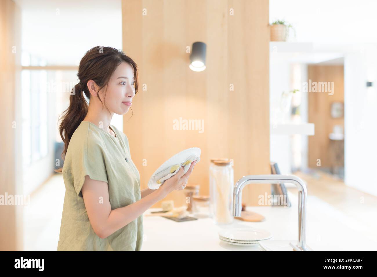Woman wiping dishes in kitchen Stock Photo